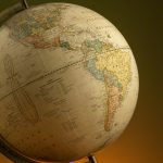 An antique globe showcasing detailed maps of North and South America with warm lighting.